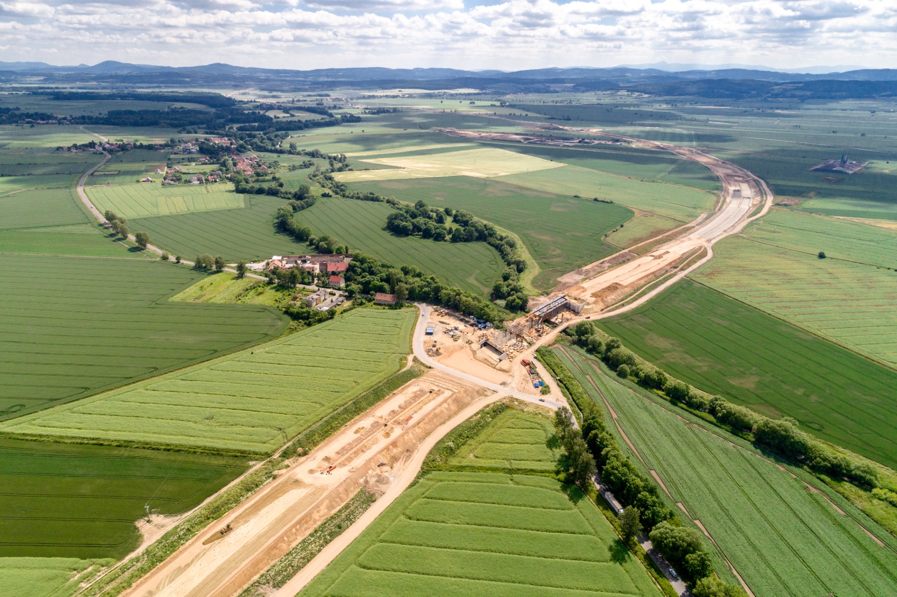 Aerial view of a highway cut through farmland, illustrating DOT-scale environmental review