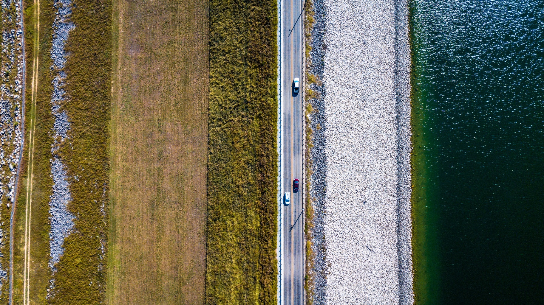 Aerial view of a causeway road with cars crossing between open water and a vegetated levee